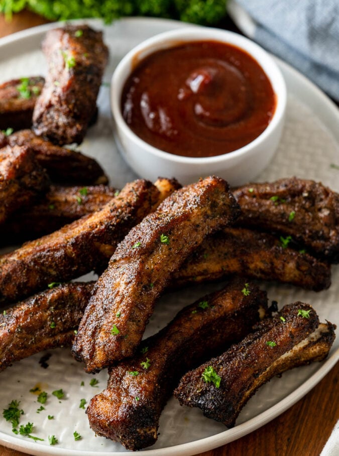 ribs on a plate with a bowl of bbq sauce