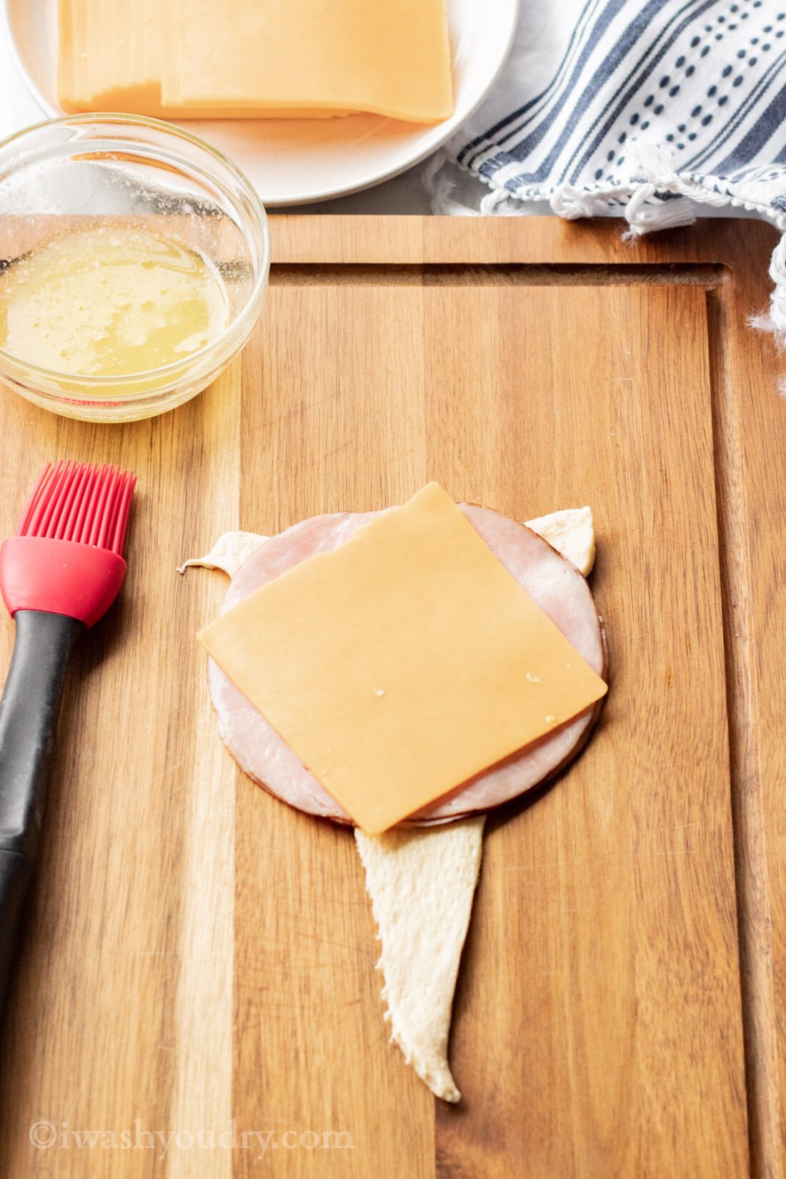 Raw dough, ham, and cheese on wood cutting board. 