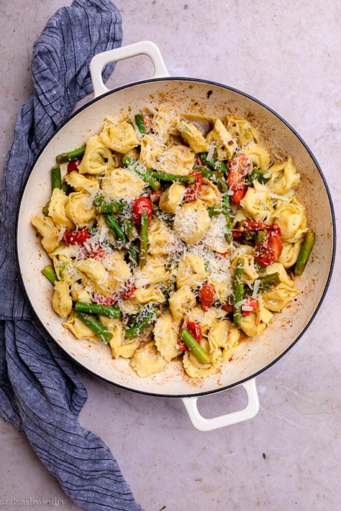 cheese tortellini in a skillet with asparagus and tomatoes