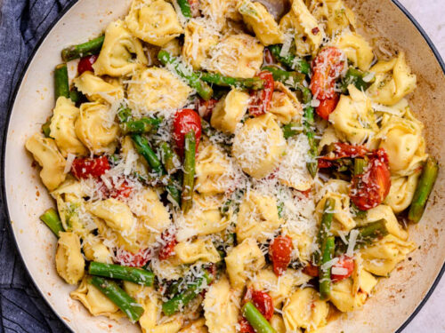 cheesy tortellini in pan with asparagus and tomatoes