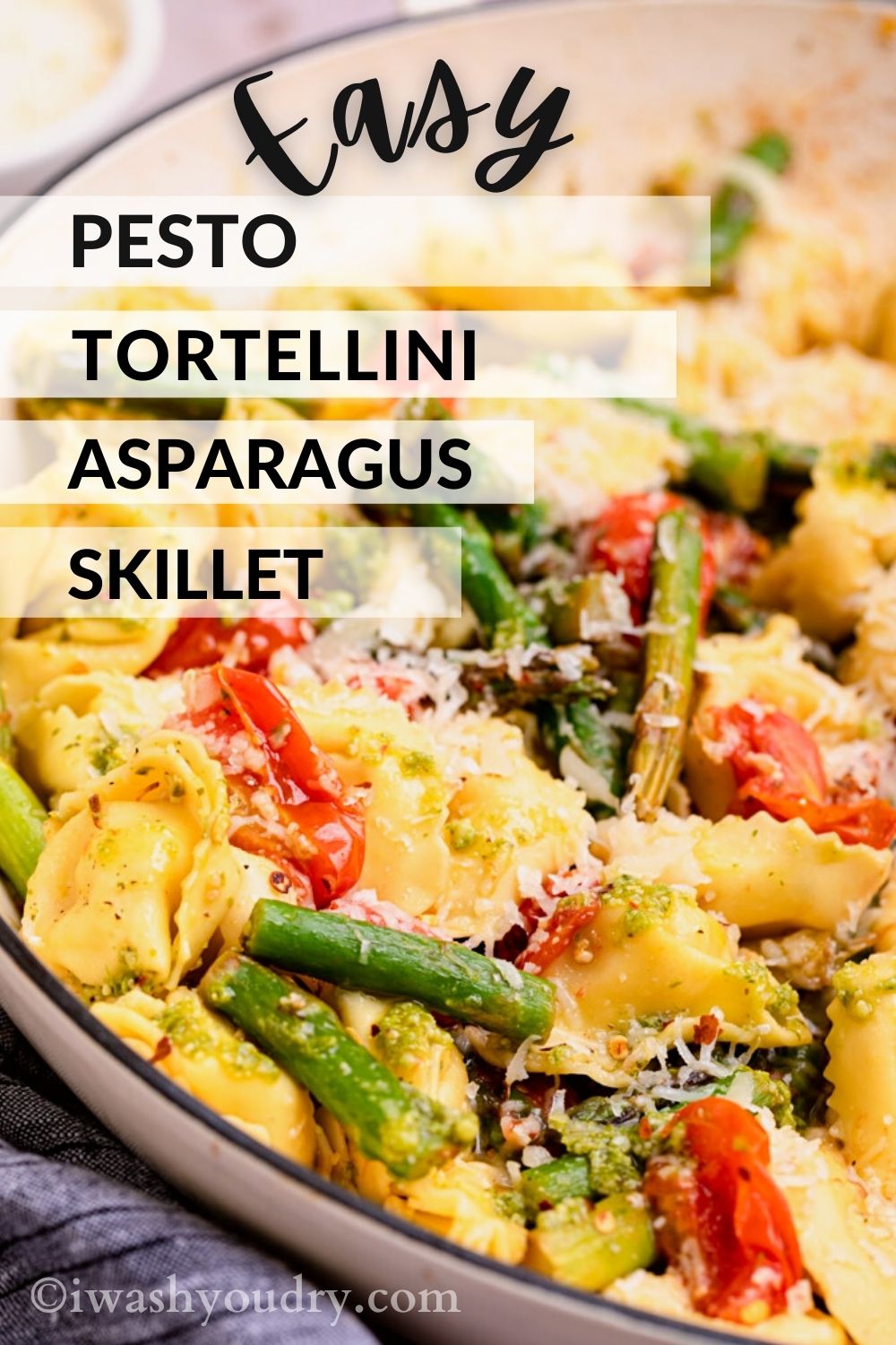 Cooked tortellini, asparagus, and tomatoes in white skillet with text overlay. 