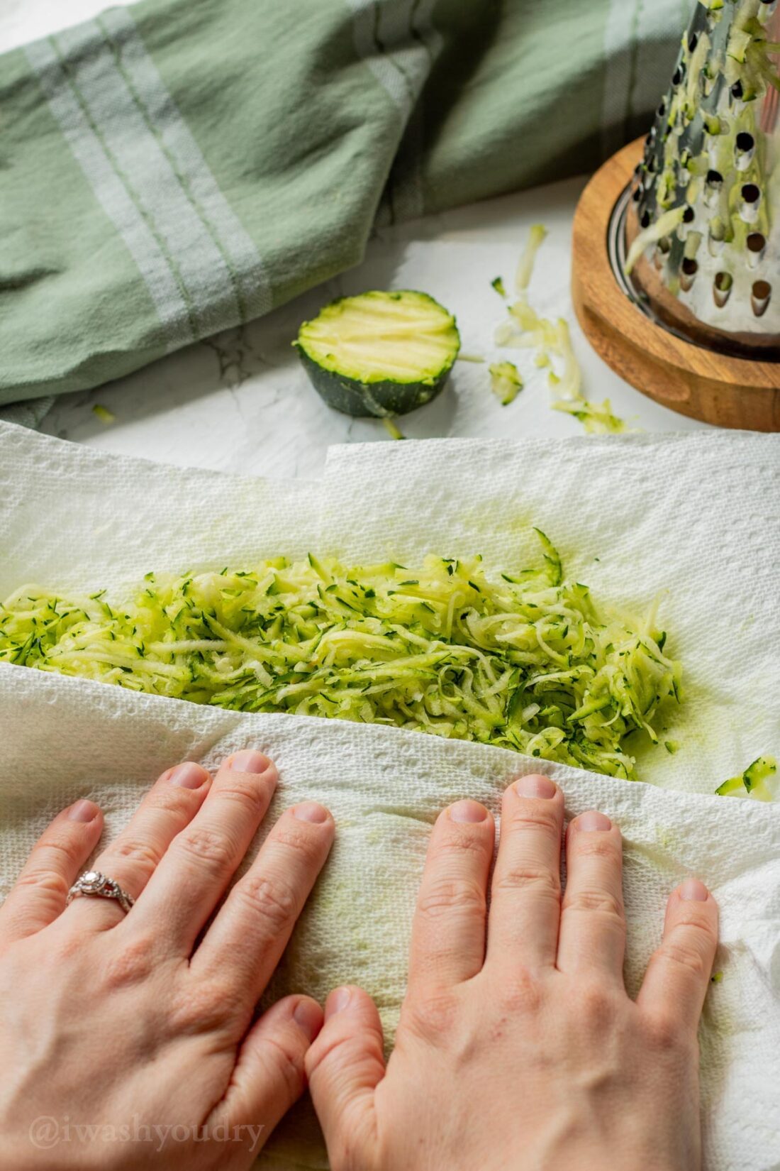 Pressing grated paper towels on grated zucchini. 