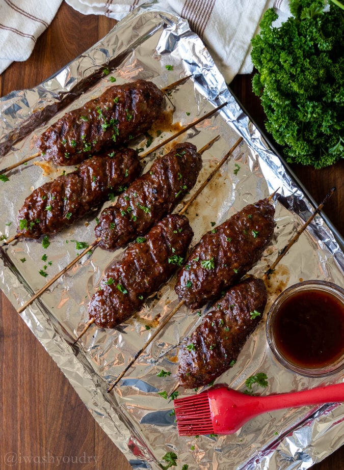 cooked meatloaf skewers on foil lined tray with bbq sauce.