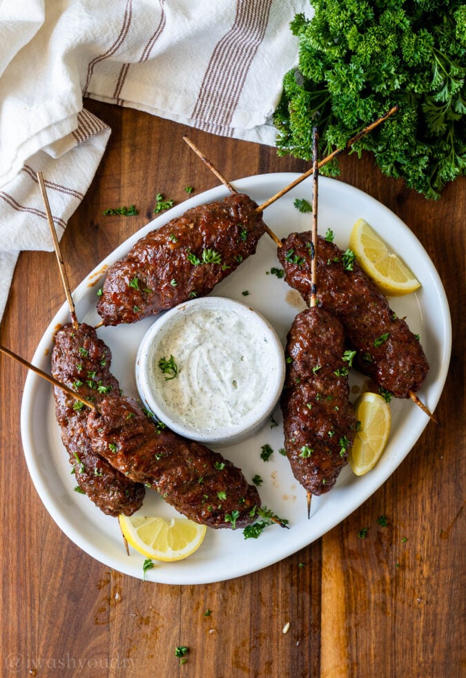 bbq meatloaf skewers on white plate with sauce and lemons.