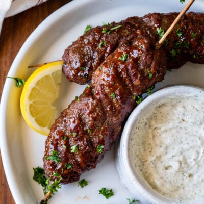 plate of meatloaf skewers with cream sauce and lemon.