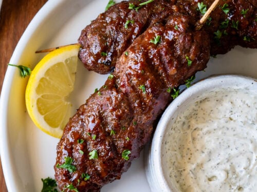 plate of meatloaf skewers with cream sauce and lemon.