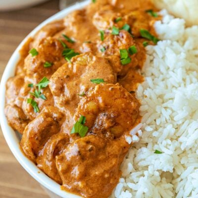 Cooked Shrimp Tikka Masala in a white bowl with rice and naan.