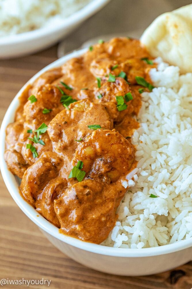Cooked Shrimp Tikka Masala in white bowl with rice and naan.