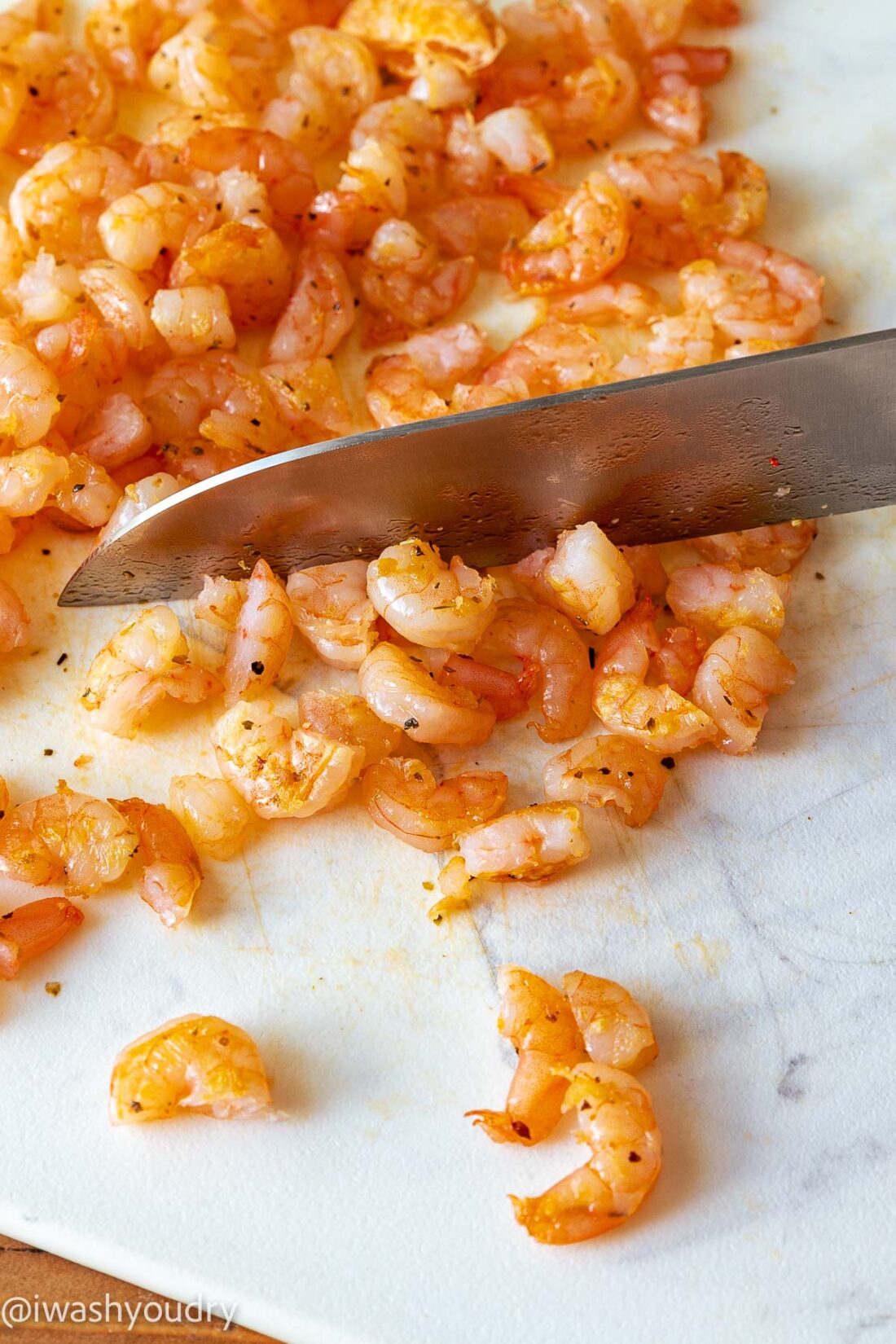 Cutting cooked shrimp on marble with knife. 