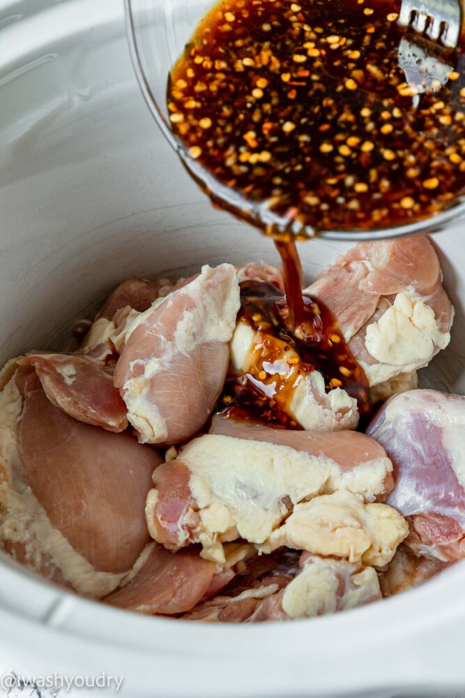pouring asian sauce over chicken thighs in slow cooker