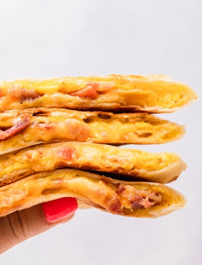 Hand holding stack of cooked breakfast quesadillas.