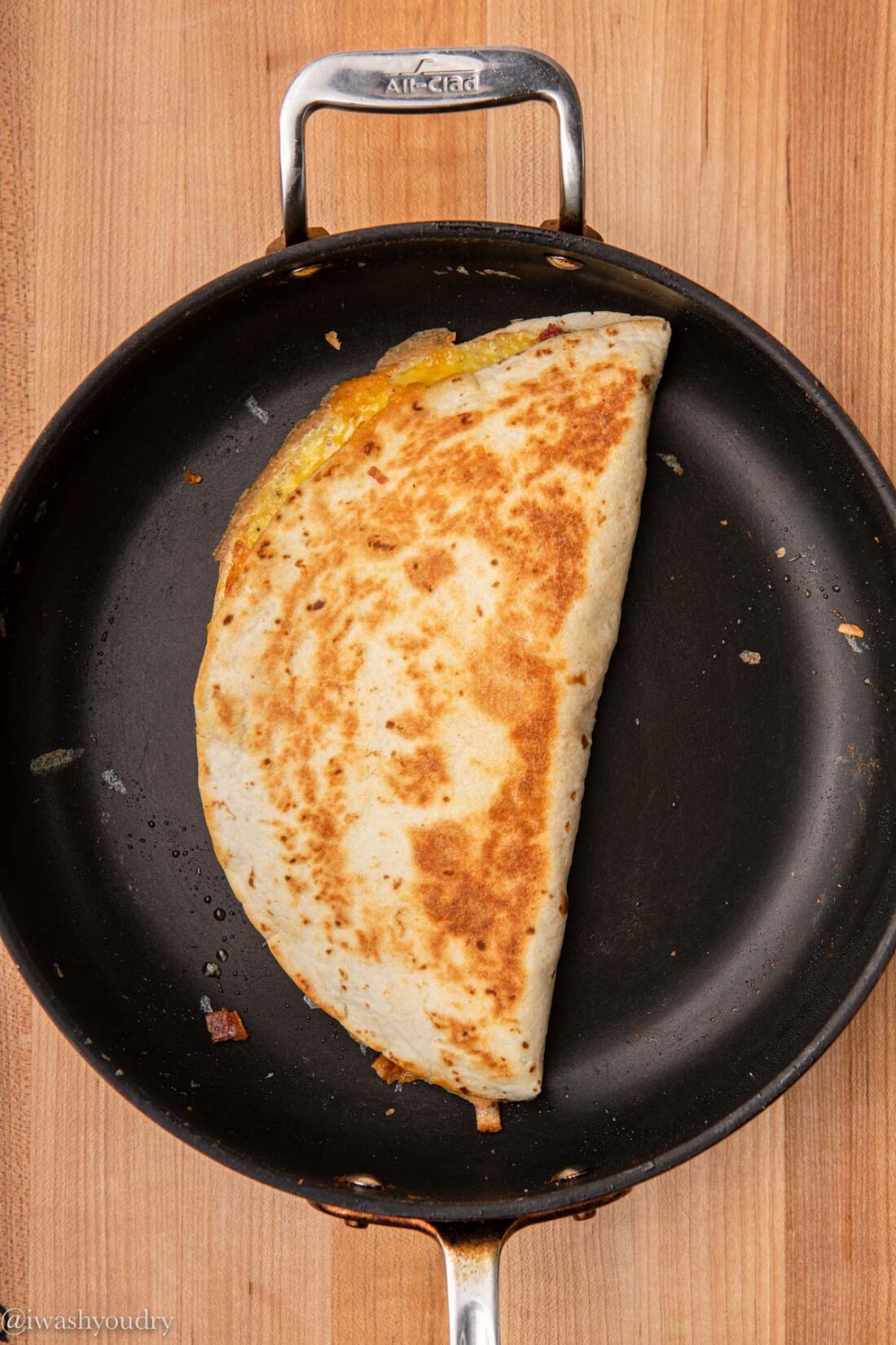 Cooked breakfast quesadilla folded in half in frying pan. 