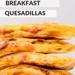 Hand holding stack of cooked breakfast quesadillas