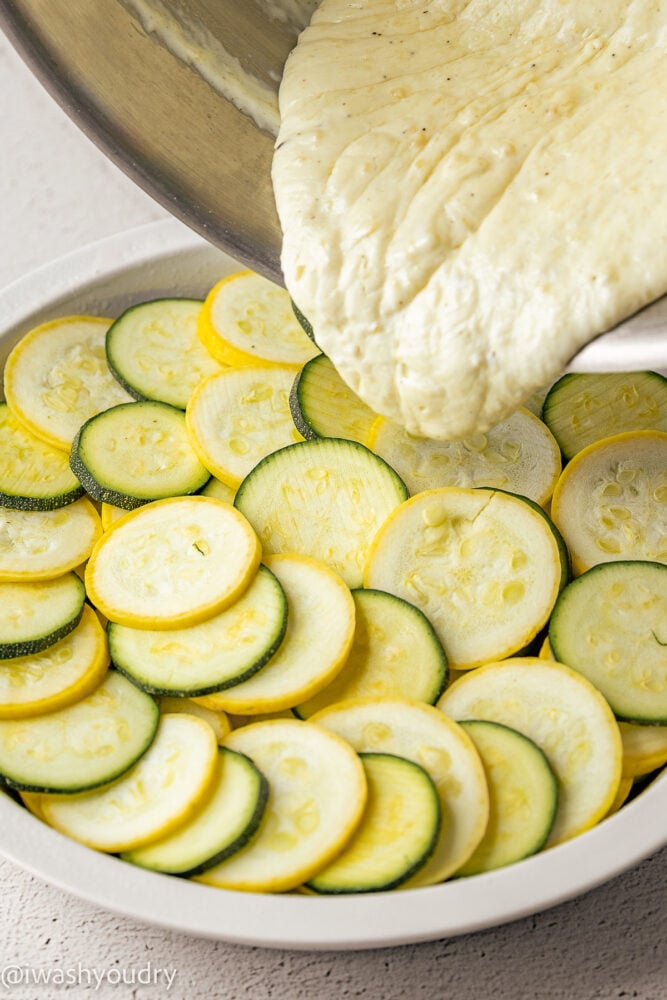 pouring cheese sauce over zucchini