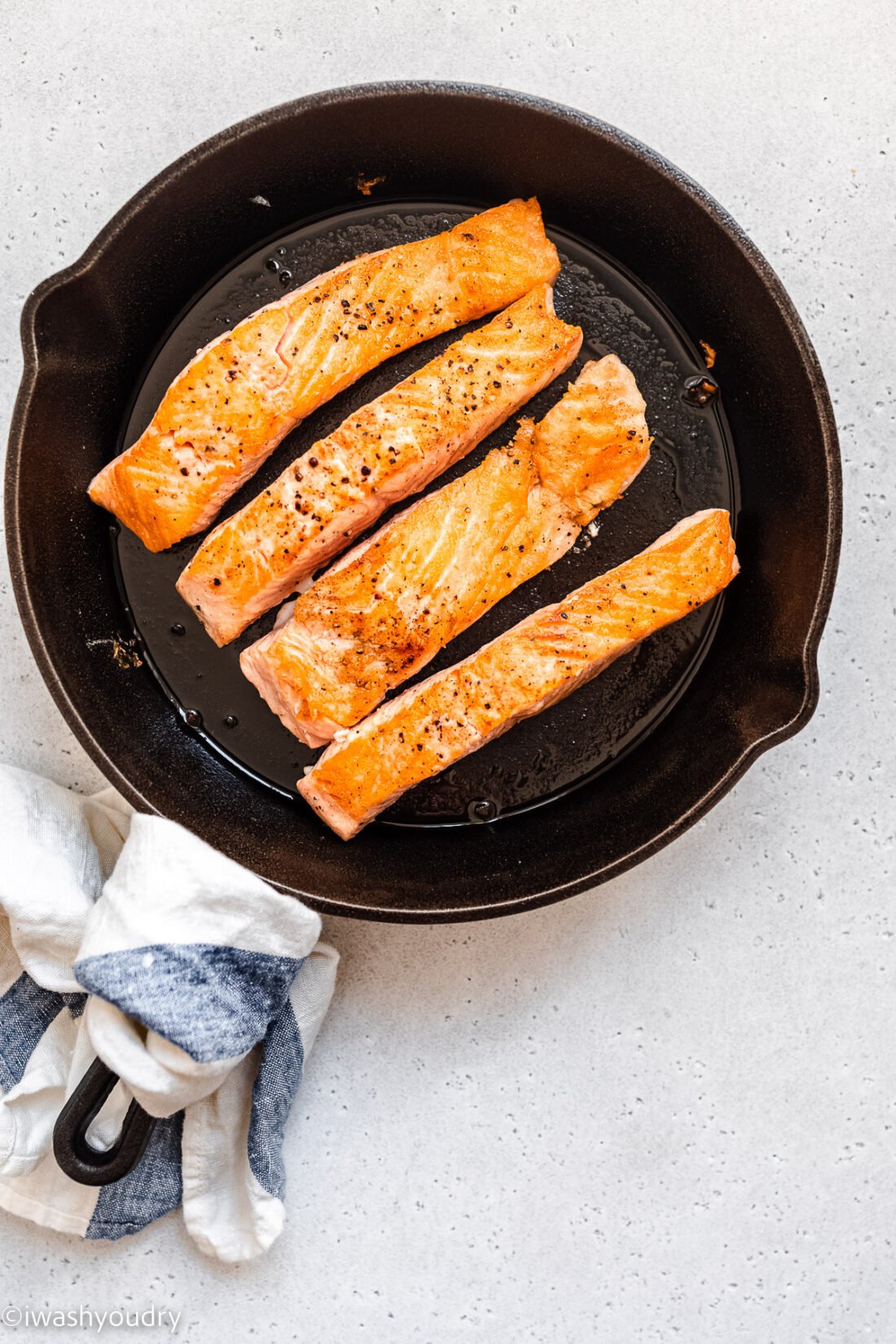 Salmon with lemon garlic cooked in a black pan. 