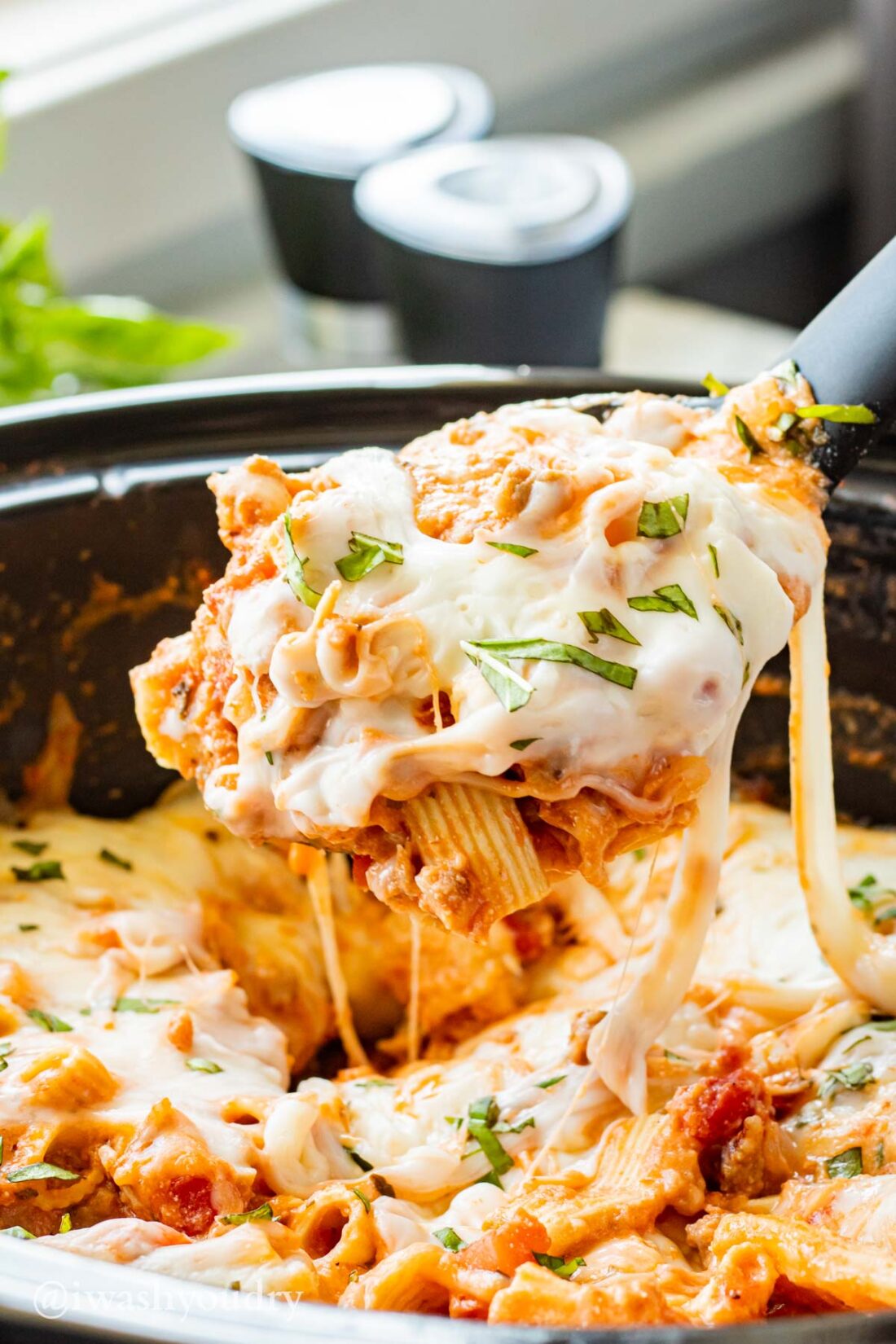 Spoonful of cooked slow cooker baked ziti above crock pot. 