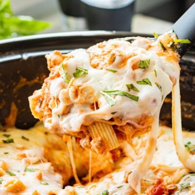 Spoonful of cooked slow cooker baked ziti above crock pot.