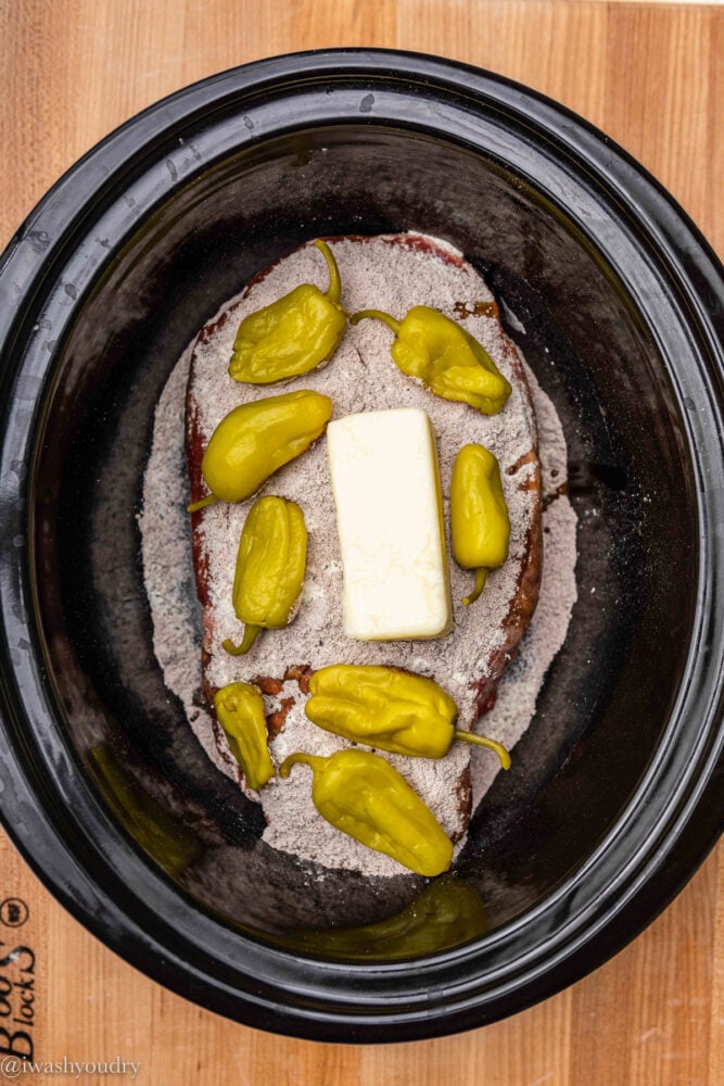 chuck roast in slow cooker with butter and peppers
