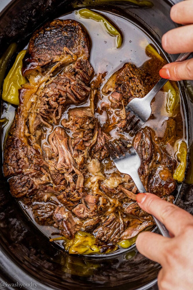 shred beef with forks in a slow cooker