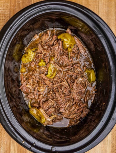 black crockpot with shredded beef and peppers