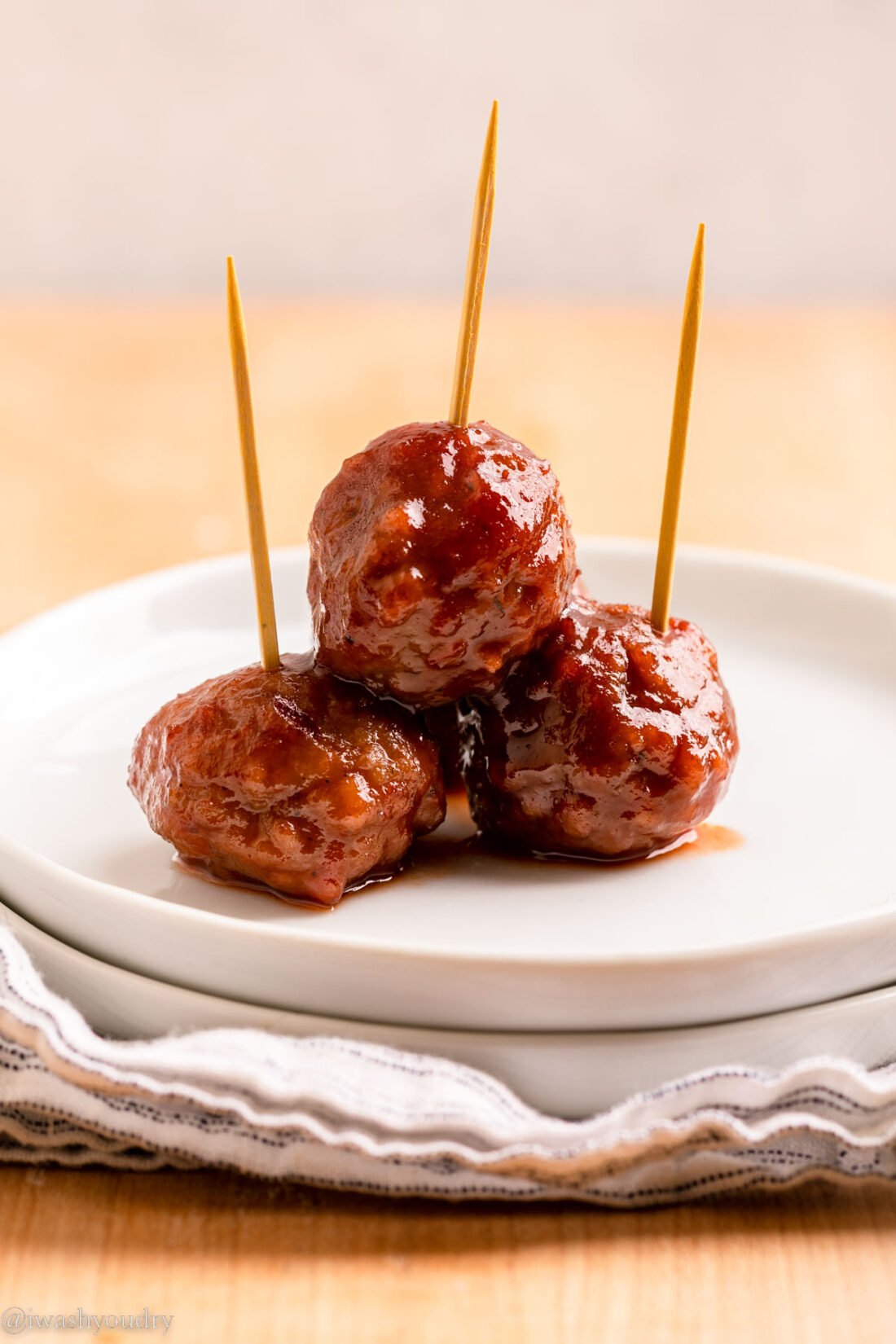 3 cocktail meatballs on white plate. 