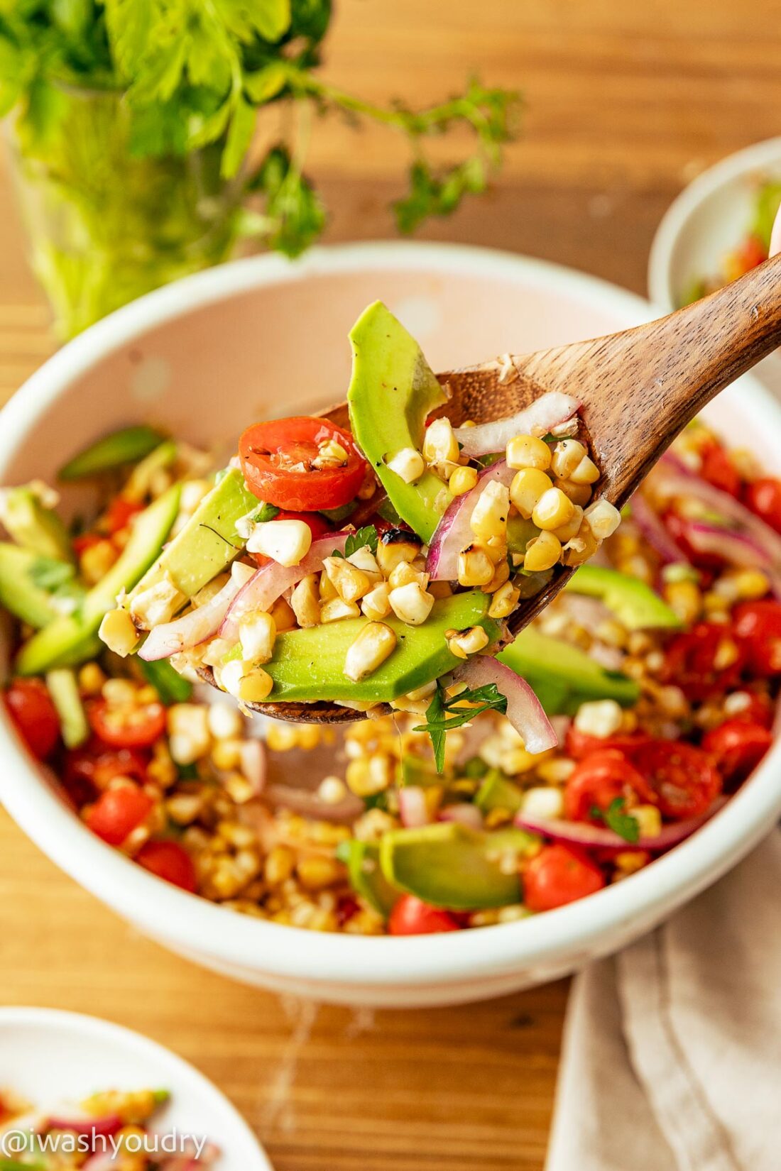 spoonful of salad with corn and avocado with tomatoes.
