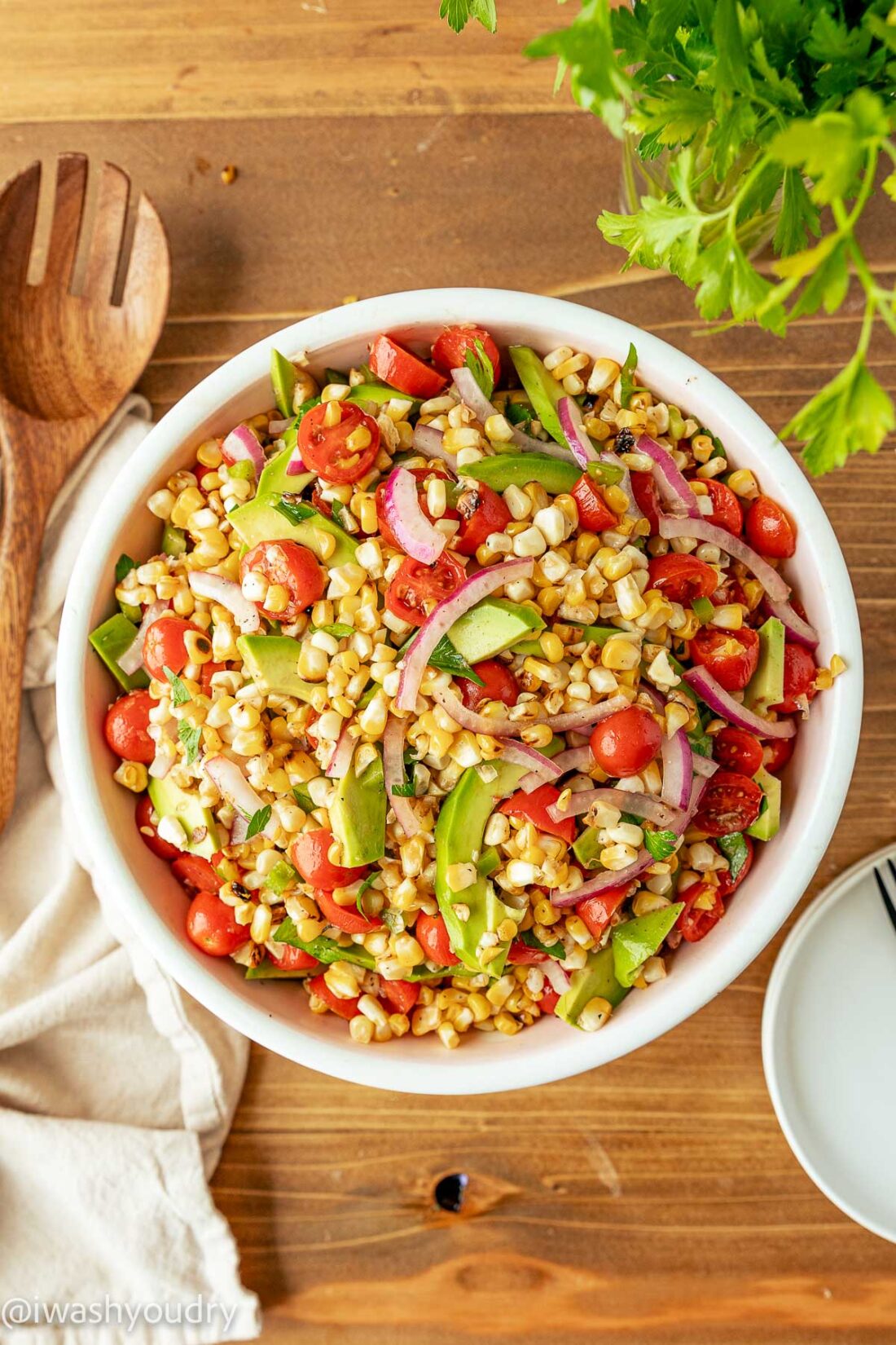 white bowl filled with corn, tomatoes and avocado salad.