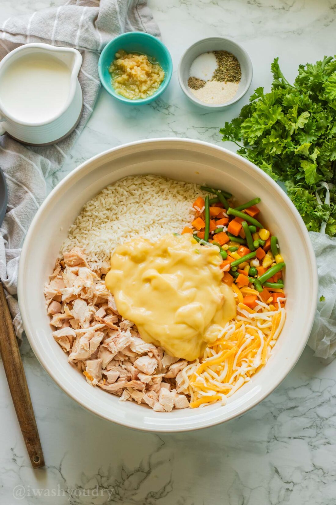Chicken, cream of chicken, veggies, cheese, and rice in bowl on marble countertop. 