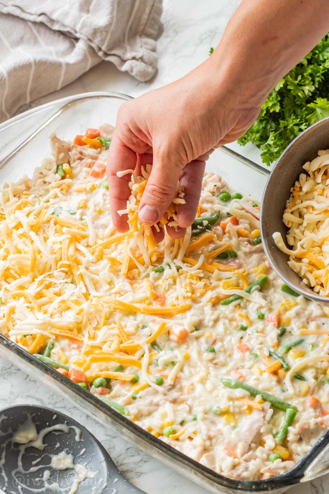 Hand sprinkling cheese on creamy chicken and rice casserole. 