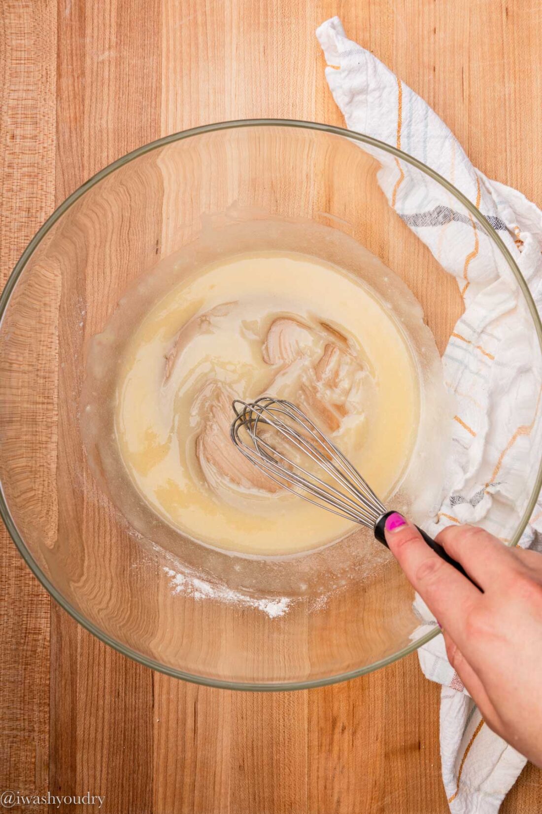 Hand whisking flour and butter in a glass bowl.