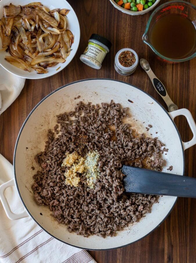 ground beef in white pan with wooden spoon