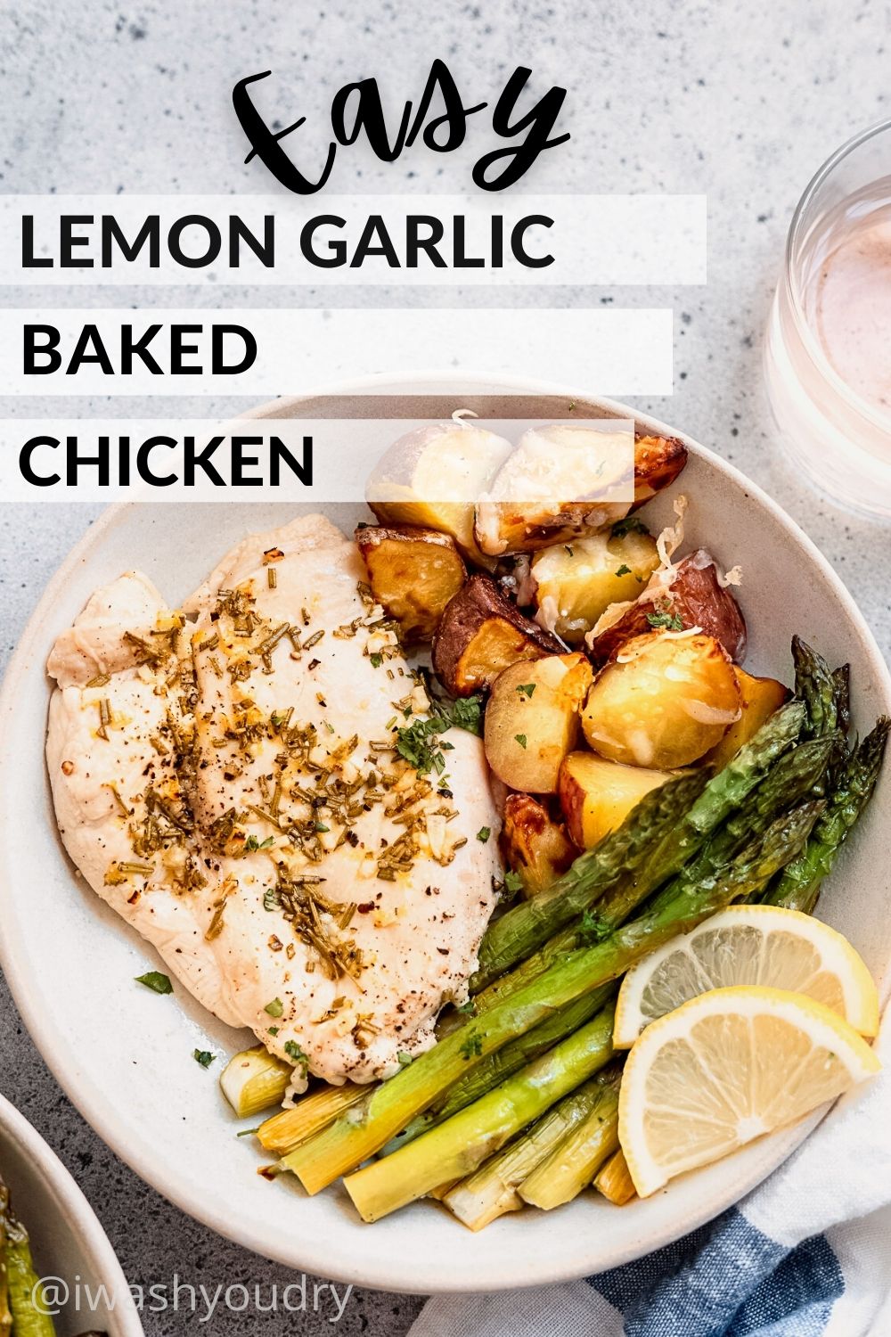 Cooked Lemon Garlic baked chicken with potatoes, asparagus, and lemon wedges on white plate.