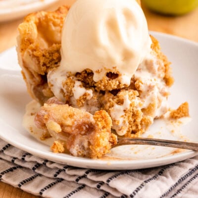 Slice of baked dutch apple pie on white plate with fork.