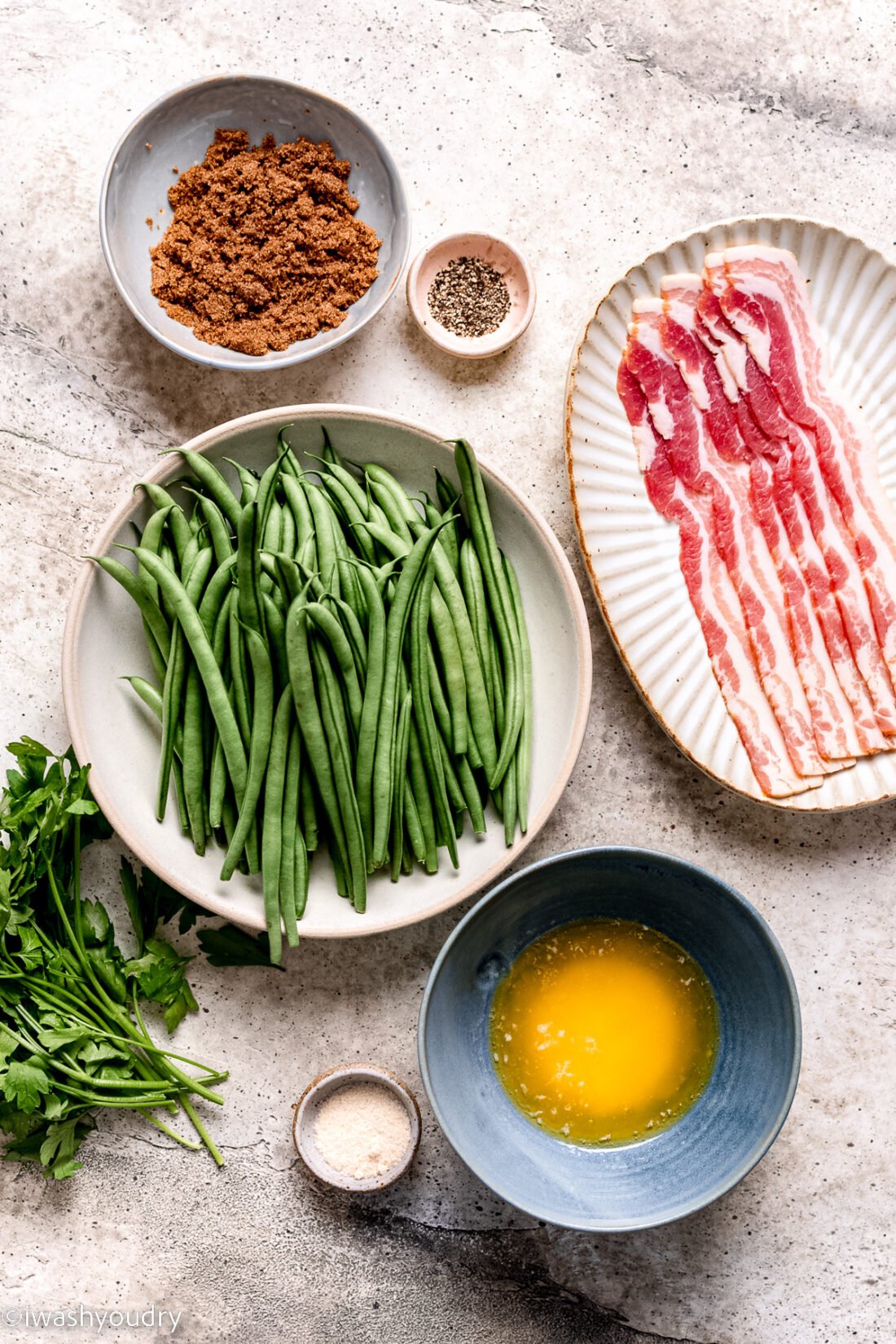 ingredients for green bean bacon bundles on white surface.