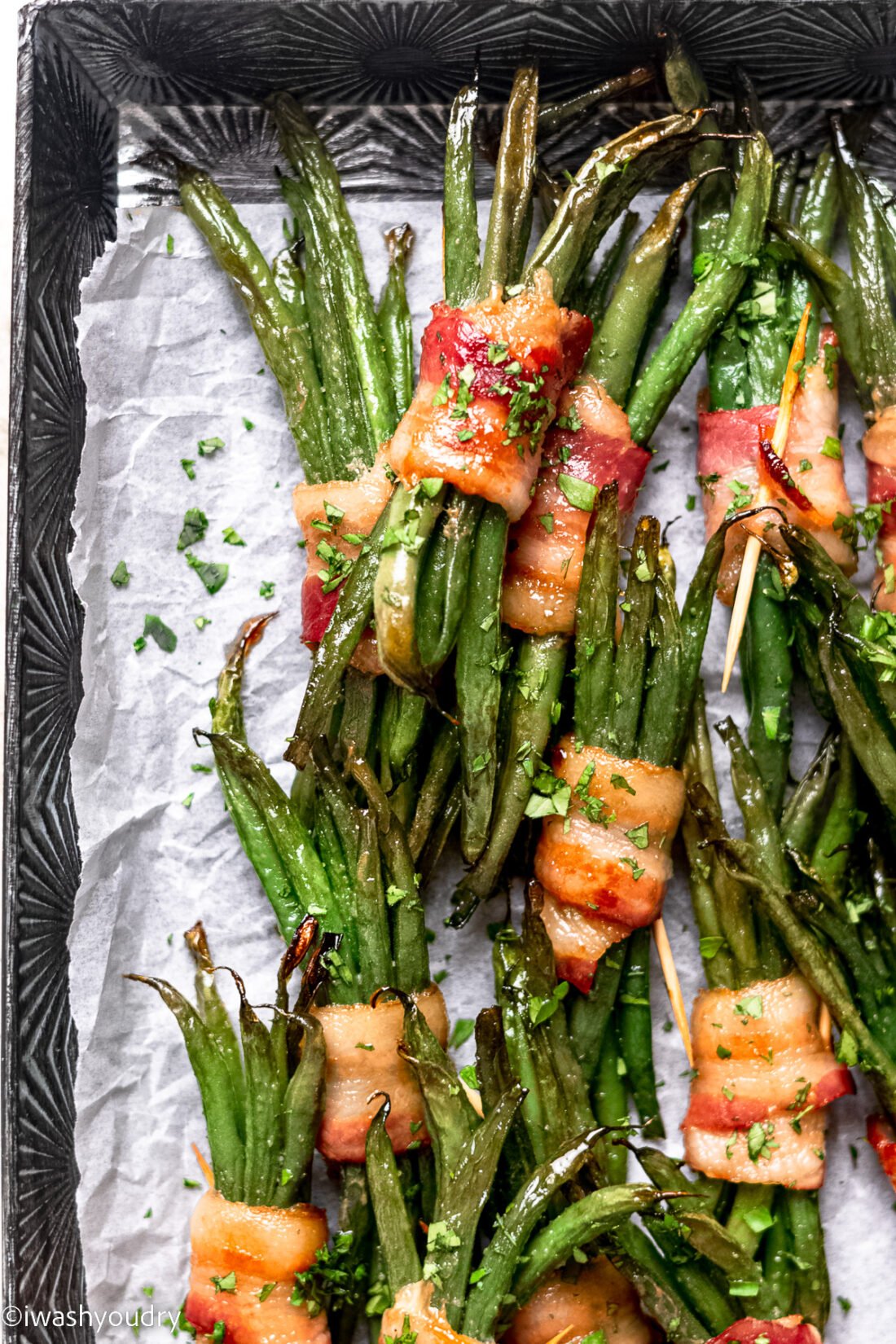 bacon wrapped green beans on a baking sheet.