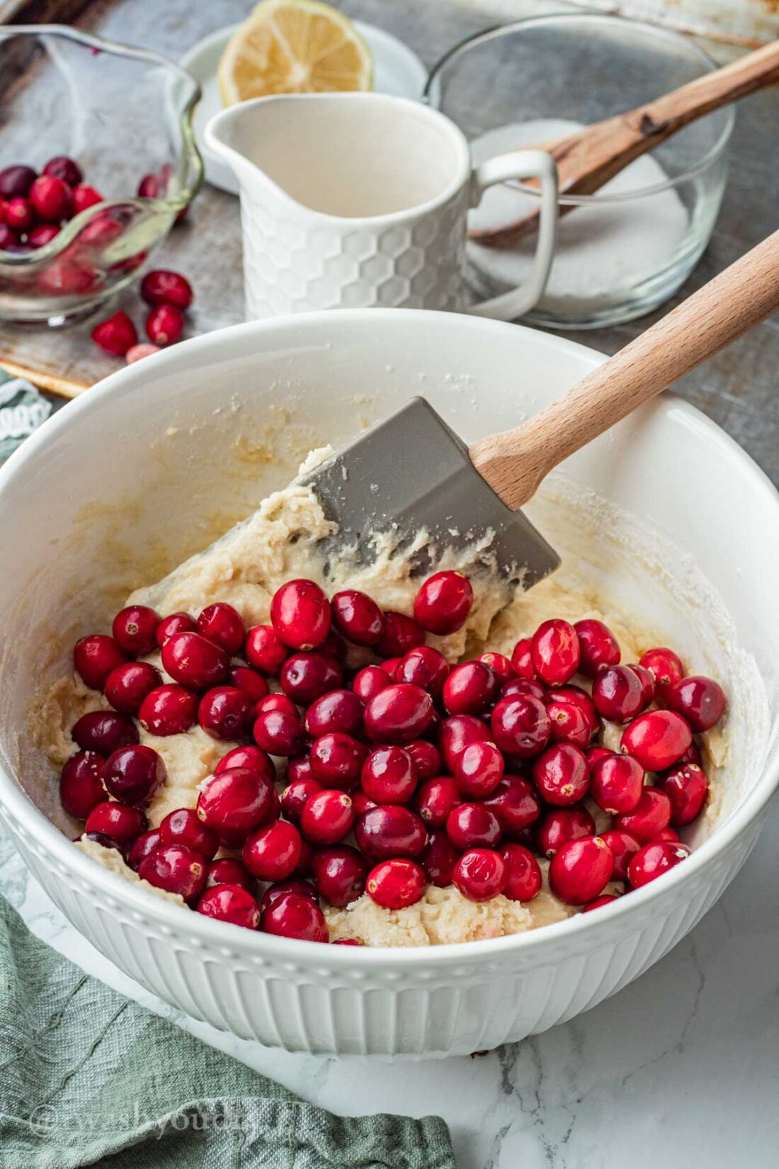 Cranberries in buttermilk batter in white mixing bowl. 