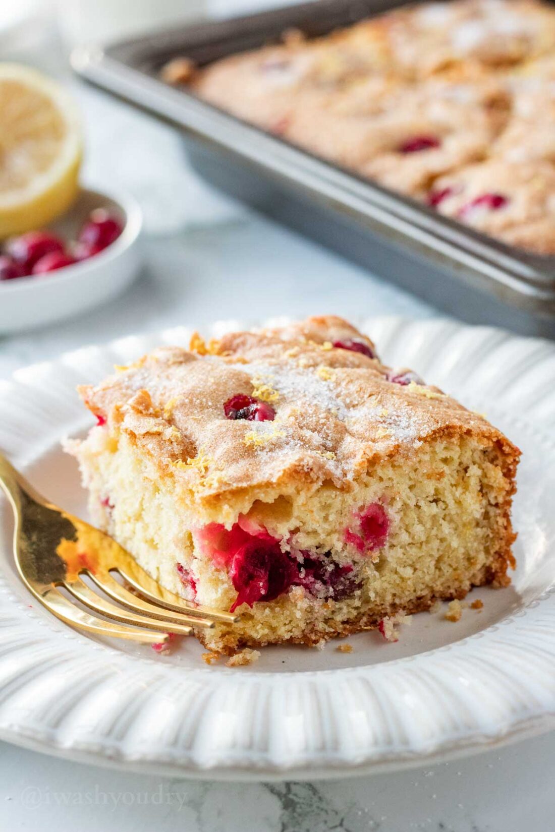 Sliced of baked Cranberry Buttermilk Cake on white plate with gold fork. 
