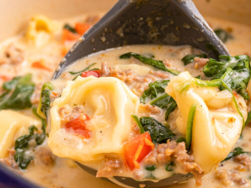 spoonful of tortellini soup with spinach and peppers.