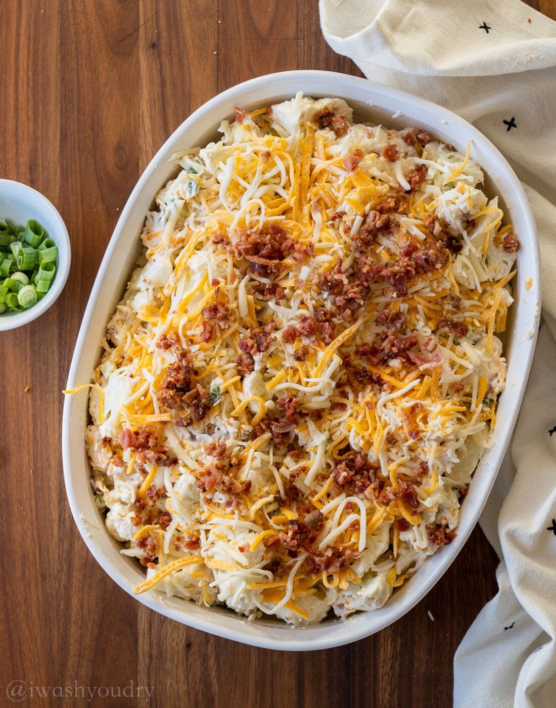 unbaked cauliflower casserole with cheese and bacon on top