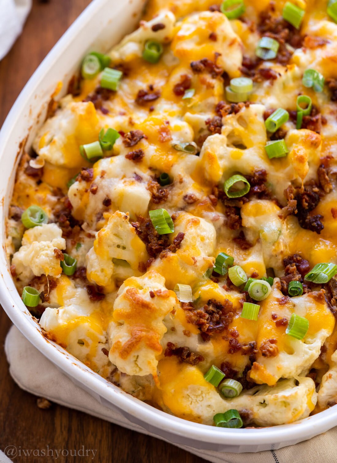 white casserole dish with loaded cauliflower, cheese and bacon.