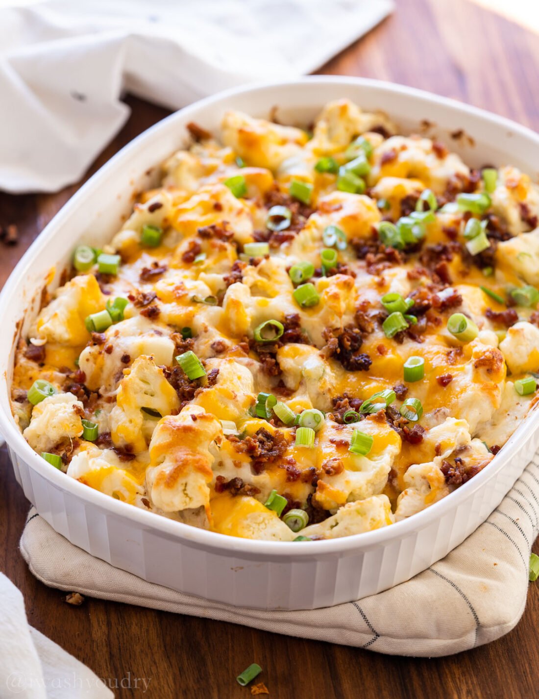 loaded cauliflower casserole in a white casserole dish with cheese and bacon
