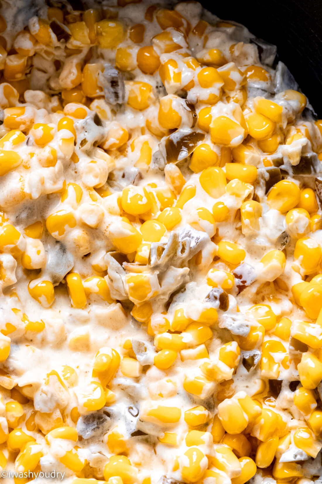 Cooked creamed corn in black slow cooker. 