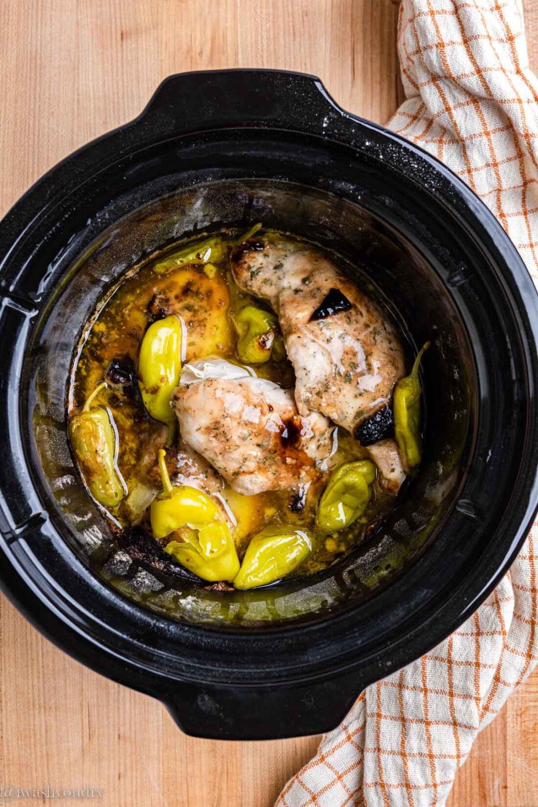 Cooked slow cooker mississippi chicken in black slow cooker. 