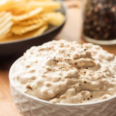 chip dip in white bowl with chips in back.