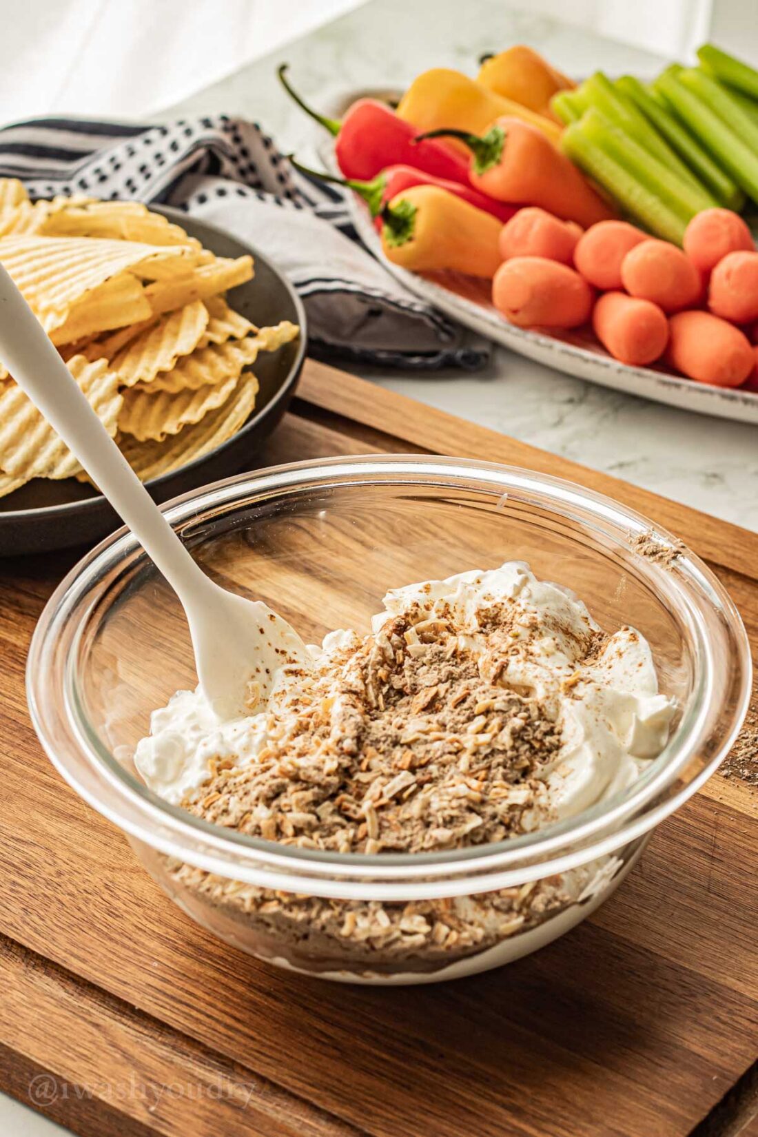 combining ingredients in a glass bowl with a white spatula. 