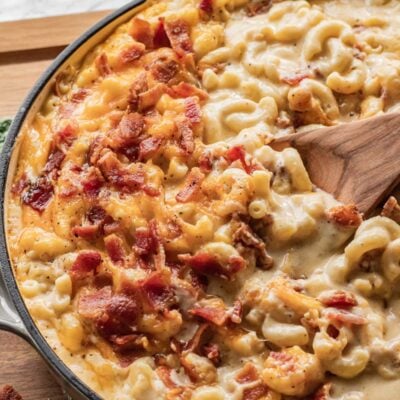 Baked Bacon Mac and Cheese in frying pan with wooden spoon.