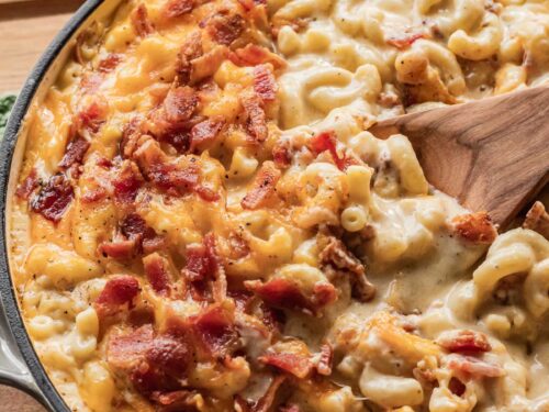Baked Bacon Mac and Cheese in frying pan with wooden spoon.