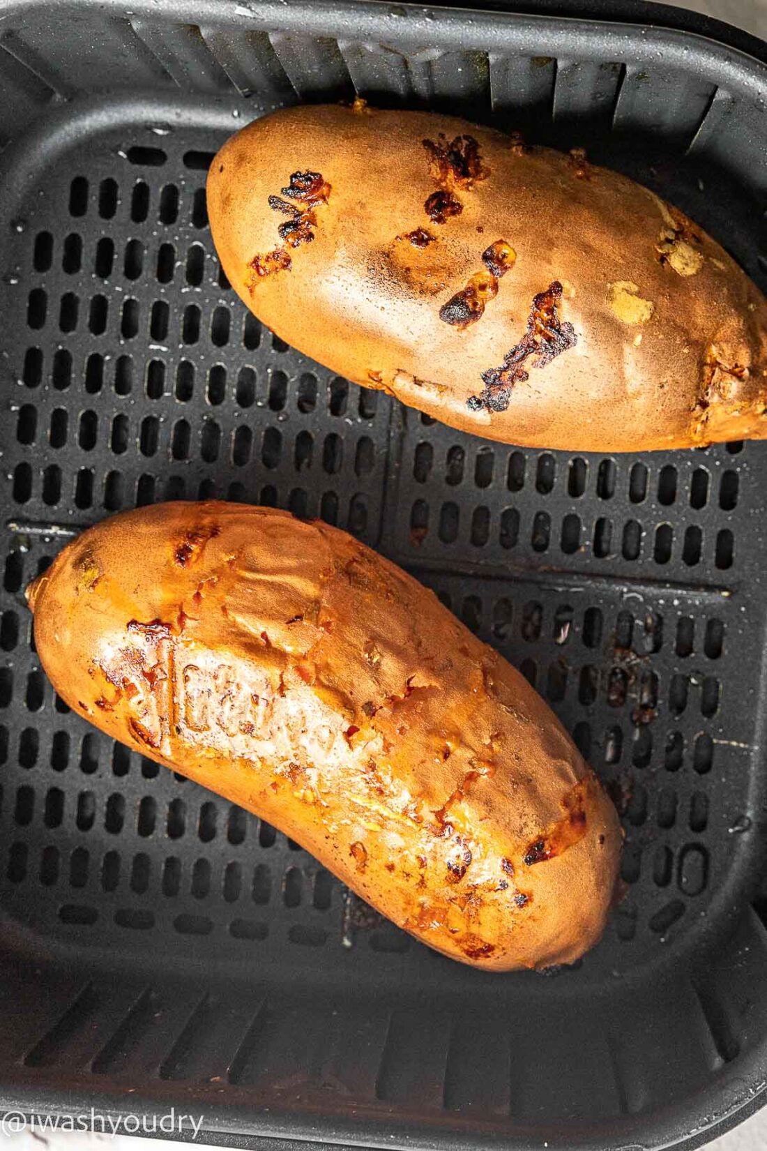 Cooked whole sweet potatoes in air fryer basket. 