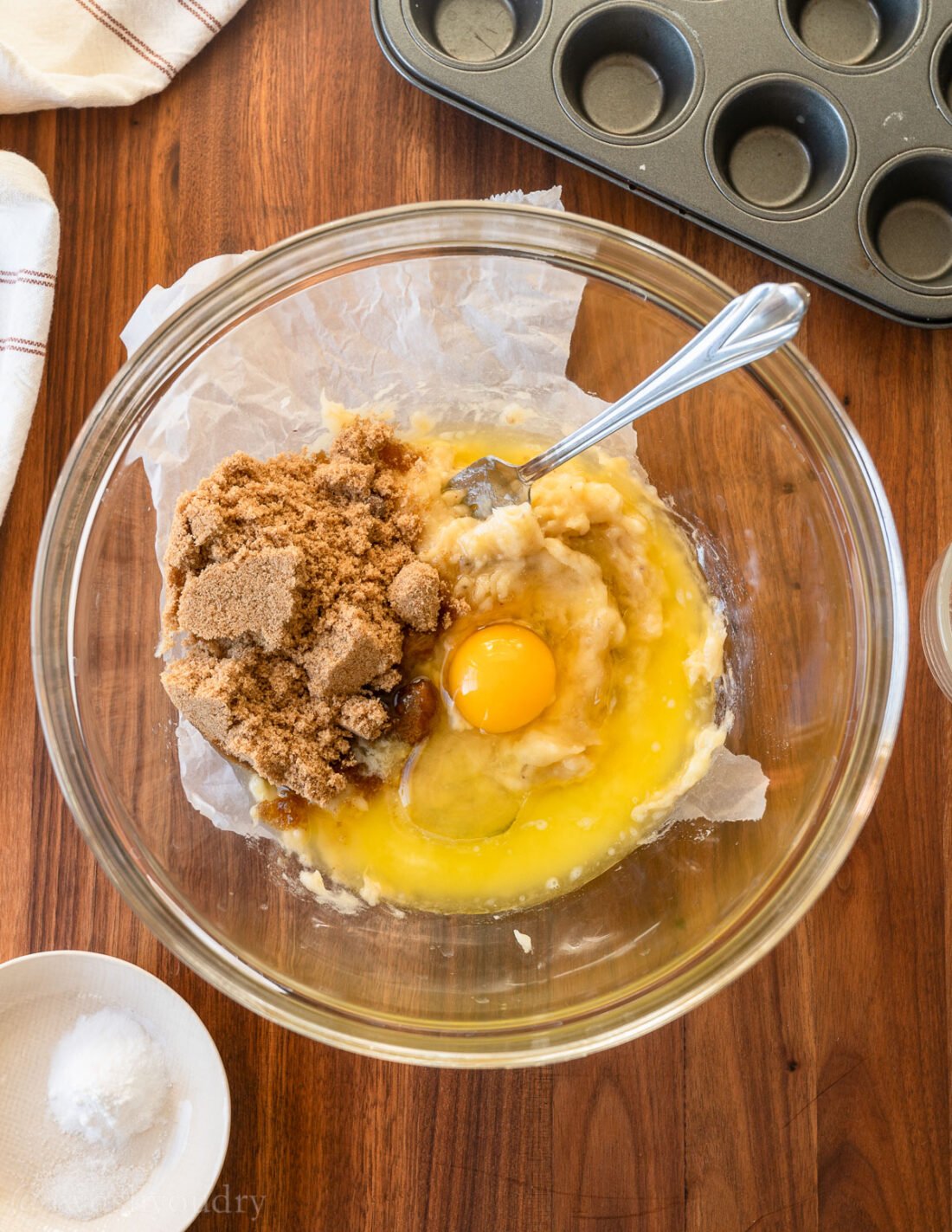 brown sugar, egg and bananas in a bowl with a fork.
