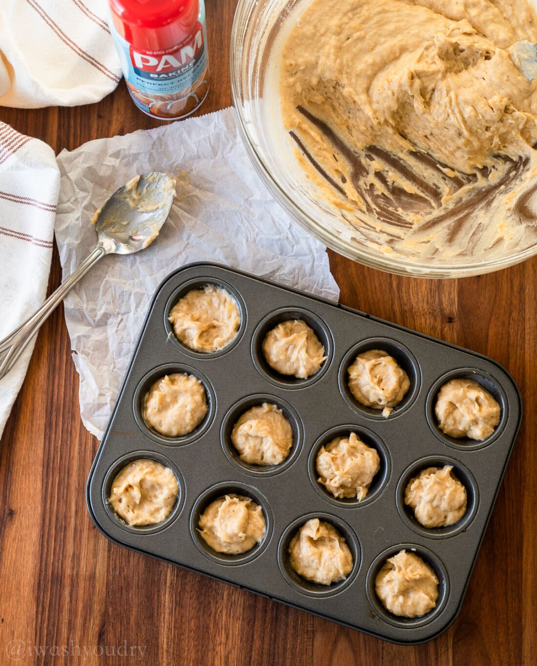 banana muffin batter in mini muffin pan with spoon nearby.